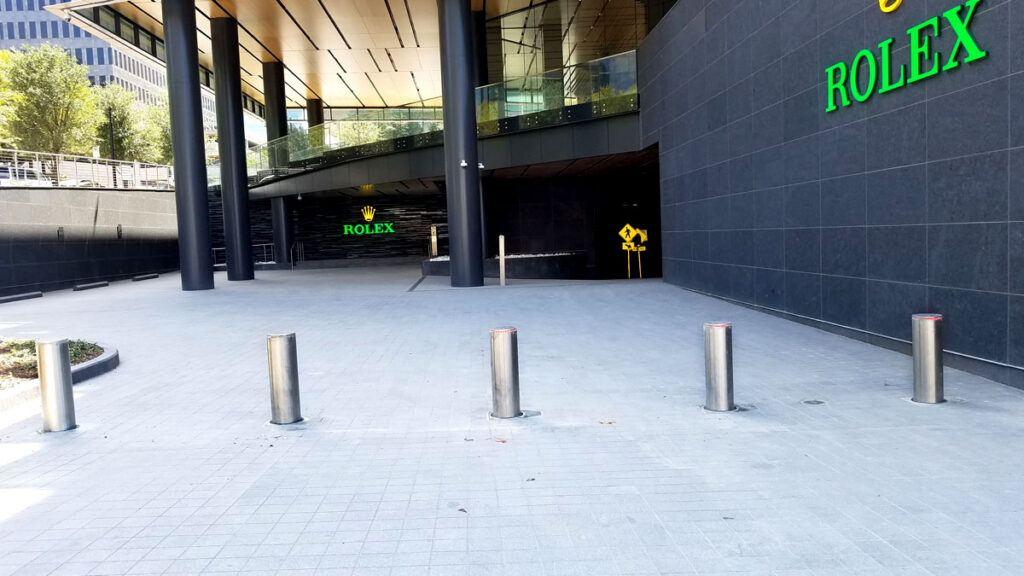 Polished stainless steel bollards installed outside a modern commercial building.