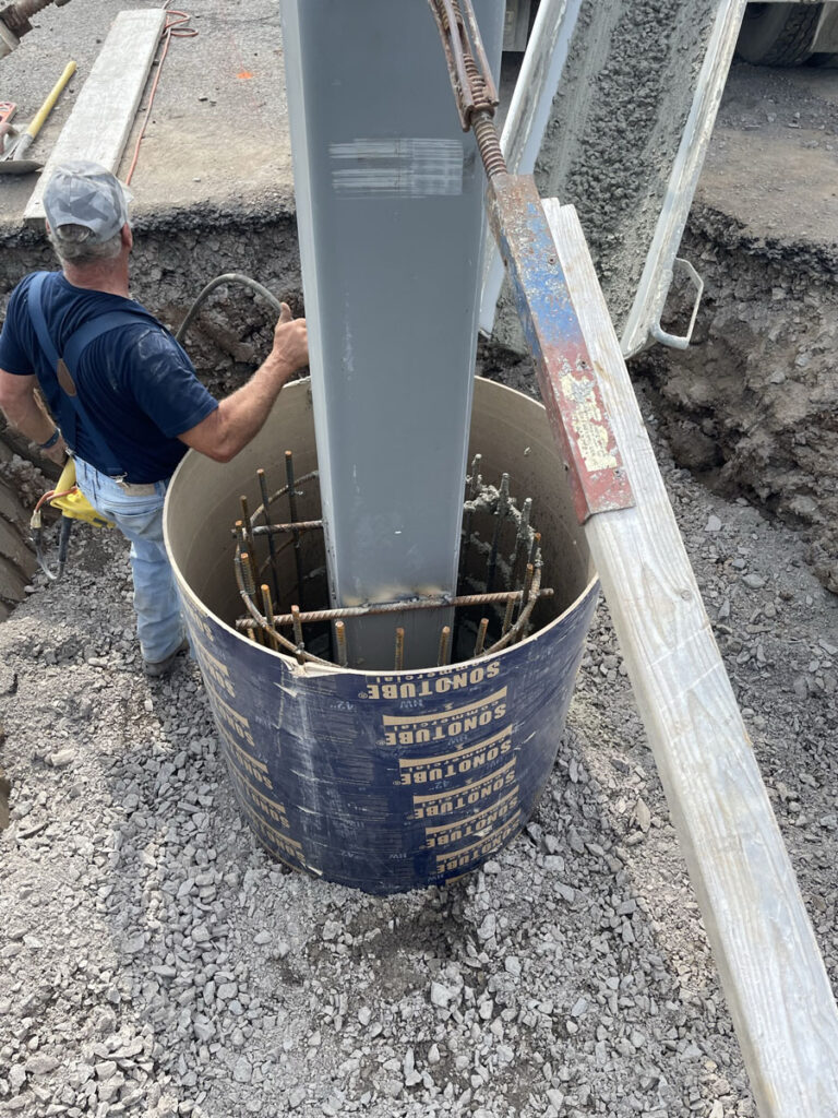 Worker installing rebar cage and deep foundation for crash-rated bollard system.